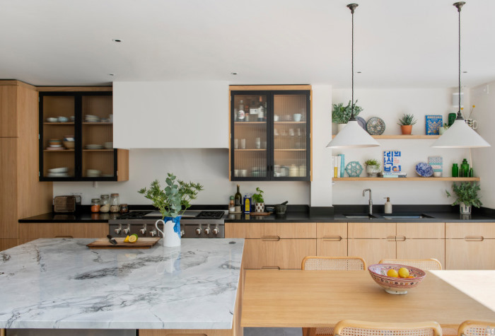 A kitchen with marble counter tops and wooden cabinets.