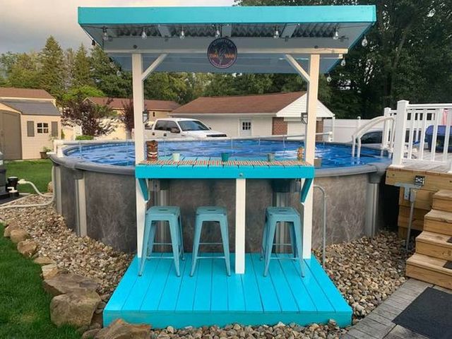 A backyard pool with a bar and stools.