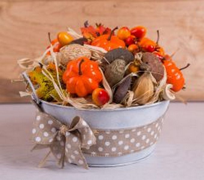 A bucket filled with pumpkins and other fall items.