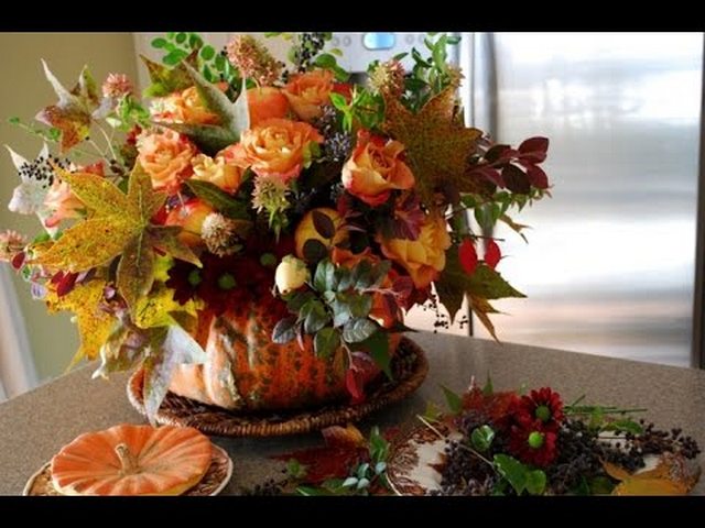 An arrangement of flowers in a pumpkin on a table.