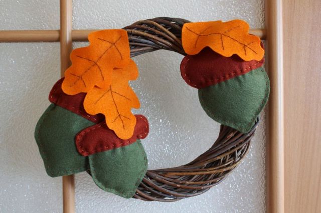 A felt wreath with acorns and leaves on it.