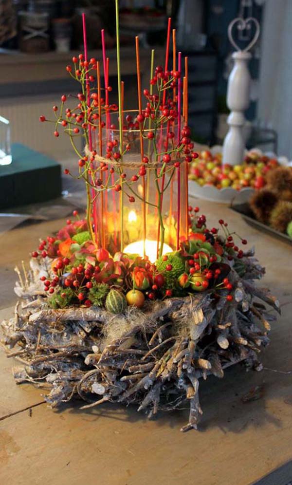 A candle surrounded by berries and sticks on a table.