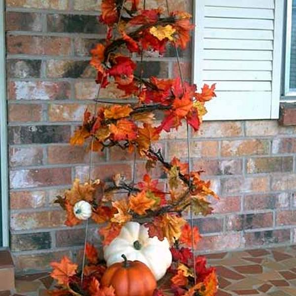 An arrangement of fall leaves and pumpkins on a front porch.