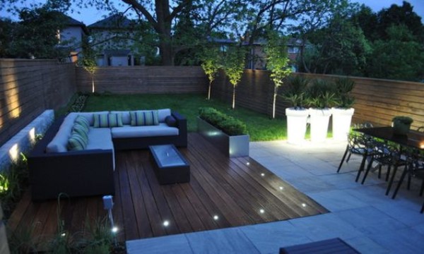 A modern backyard with outdoor furniture and lighting.
