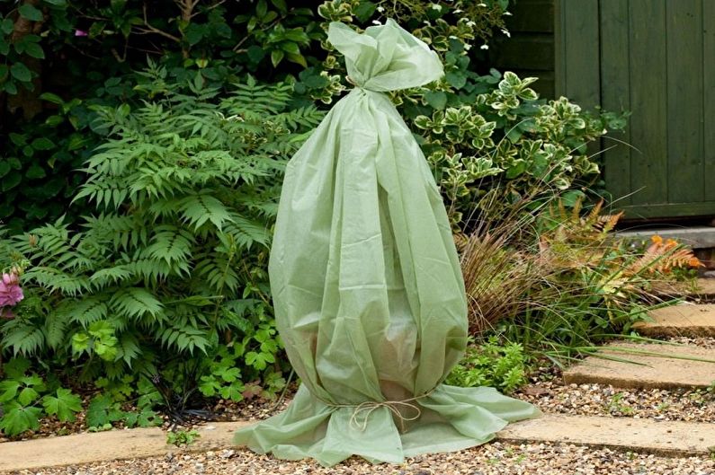 A green bag sitting on the ground in front of a house.