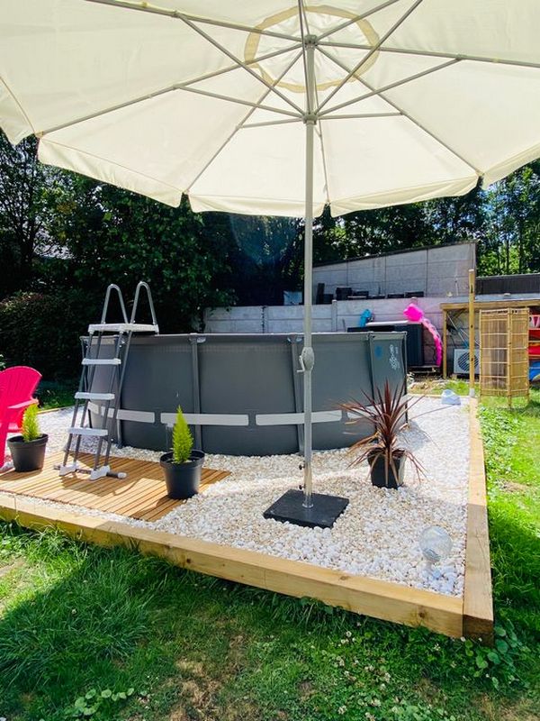 A swimming pool in a backyard with an umbrella.