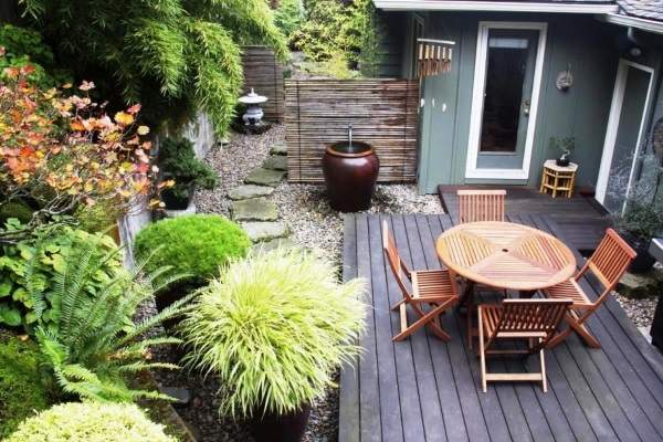 A small backyard with a wooden deck and wooden furniture.