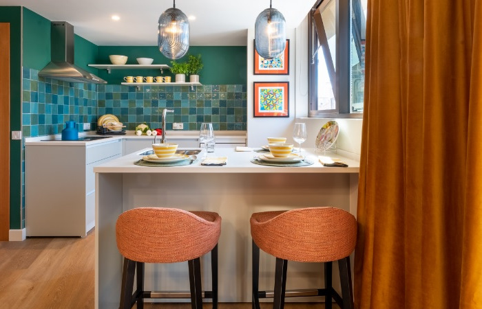 A kitchen with orange stools and green walls.