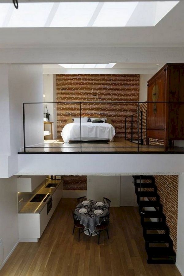 A lofted bedroom with stairs and a lofted bed.