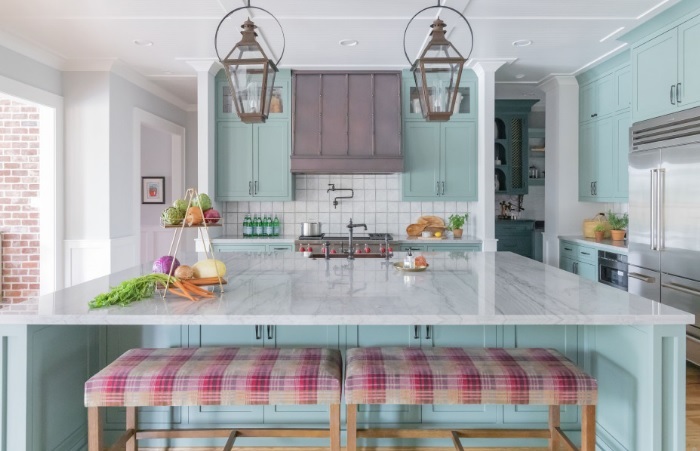 A kitchen with blue cabinets and pink stools.