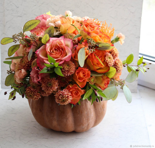 An arrangement of flowers in a pumpkin on a window sill.