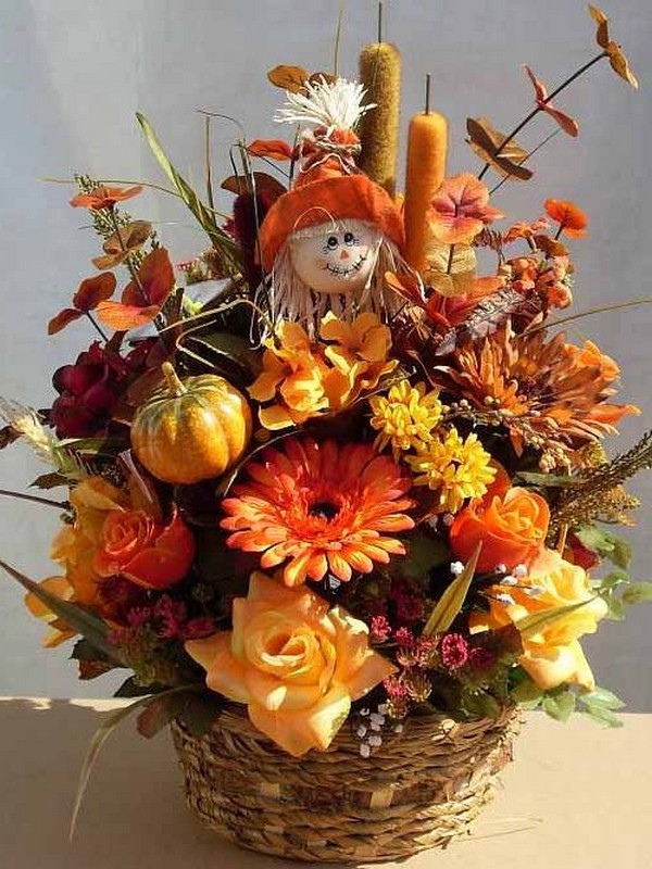 A basket filled with fall flowers and a scarecrow.