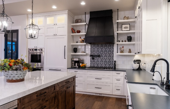 A kitchen with white cabinets and black counter tops.