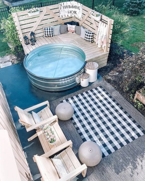 A backyard with a hot tub and chairs.