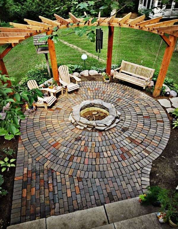 A brick patio with a fire pit in the middle.