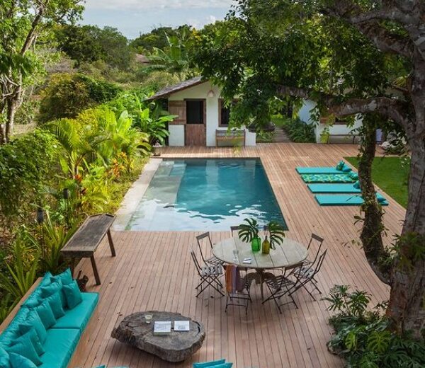 A wooden deck with a pool and lounge chairs.