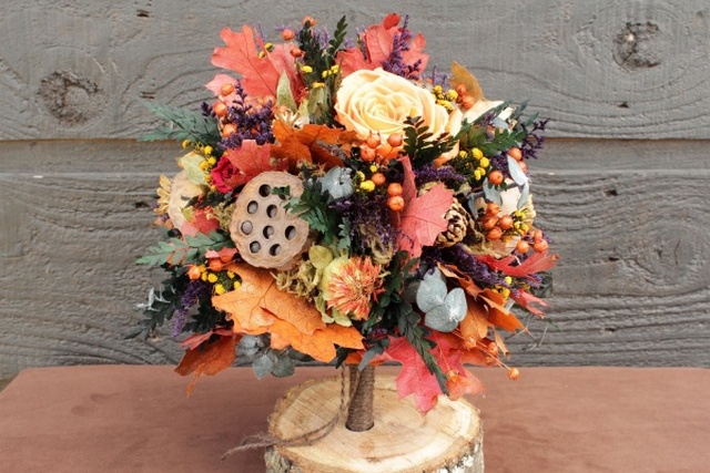 A bouquet of fall flowers on a wooden stump.