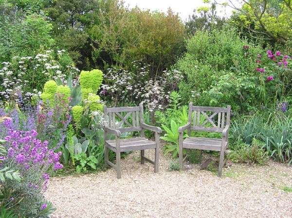 Two wooden chairs sit in the middle of a gravel garden.