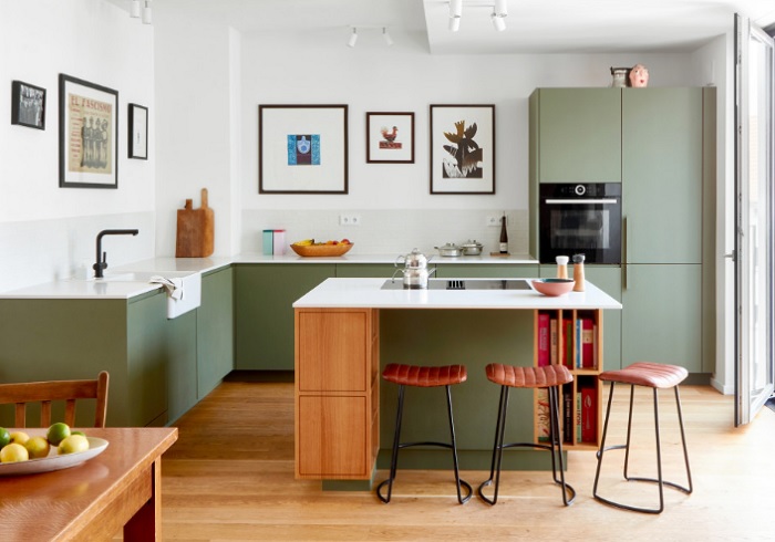 A kitchen with green cabinets and stools.