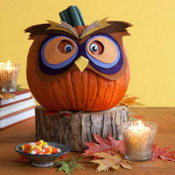 An owl pumpkin decorated with candy and candles.