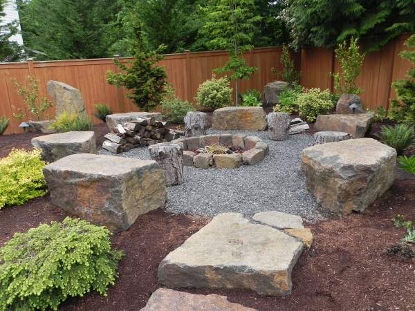 A backyard with a fire pit and rocks.
