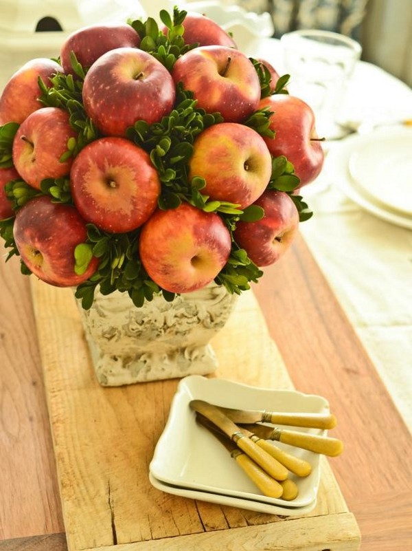 An arrangement of apples in a vase on a table.