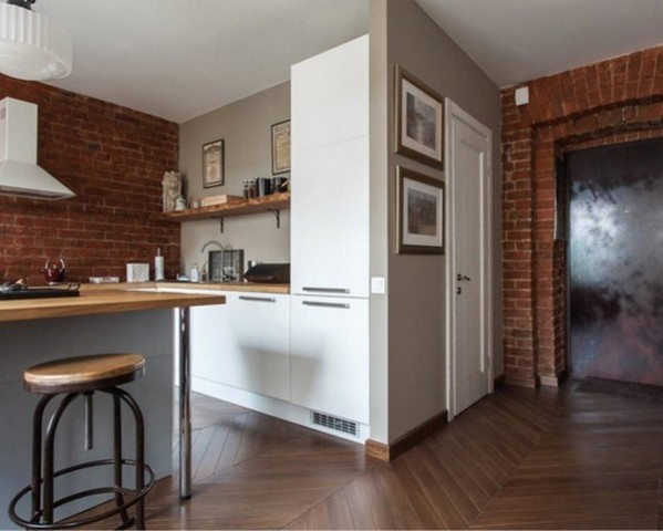 A kitchen with a brick wall and wooden floors.