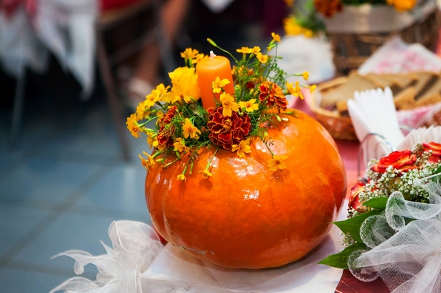 A pumpkin with flowers on it sits on a table.