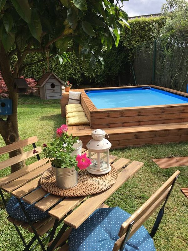 A backyard with a wooden deck and a swimming pool.