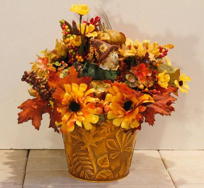 A gold pot filled with fall flowers and leaves.