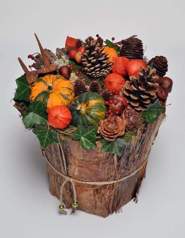 A wooden pot filled with pumpkins, ivy and holly.