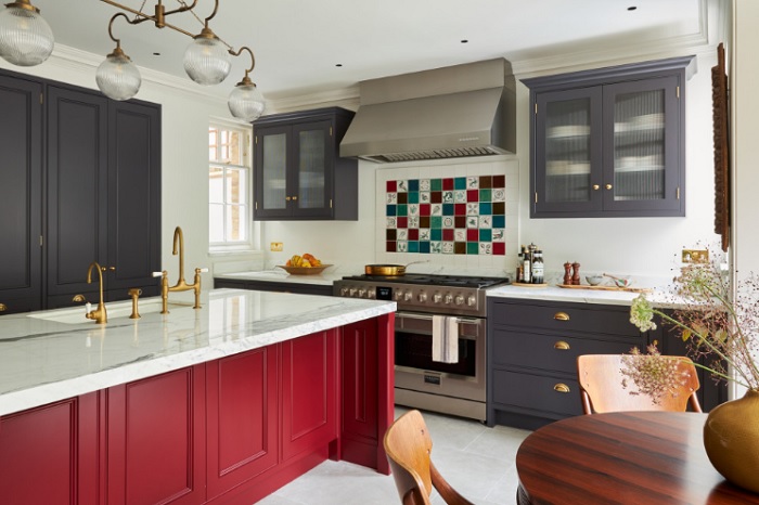 A kitchen with red cabinets and marble counter tops.