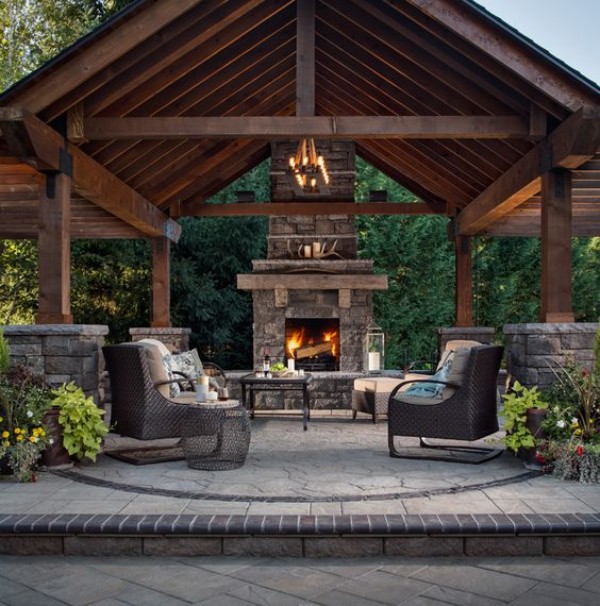 A stone patio with a fireplace and seating area.
