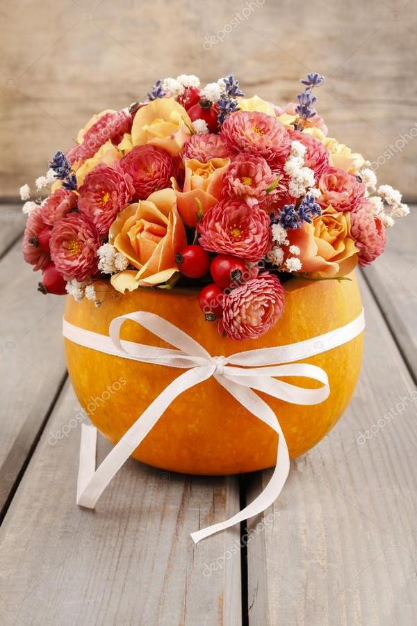 A pumpkin with flowers in it on a wooden table.