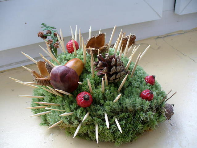 A hedge with moss and pine cones on top.