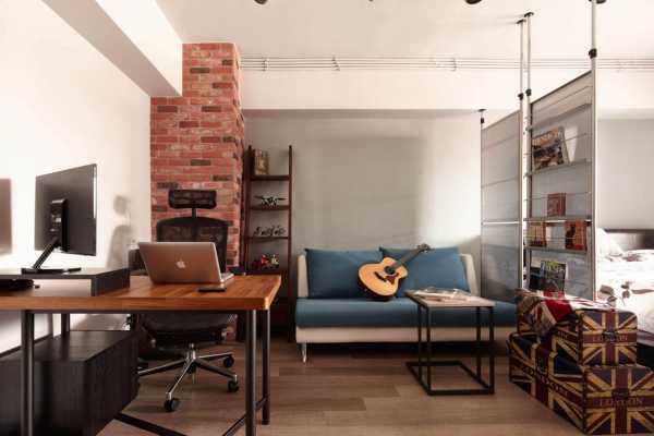 A room with a desk and a guitar in it.