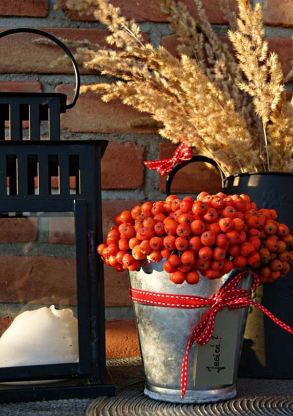 A bucket of berries and a lantern on a table.