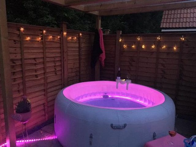 An inflatable hot tub in a backyard with pink lights.