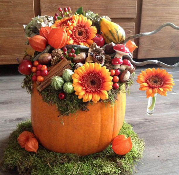 A pumpkin decorated with flowers and moss.