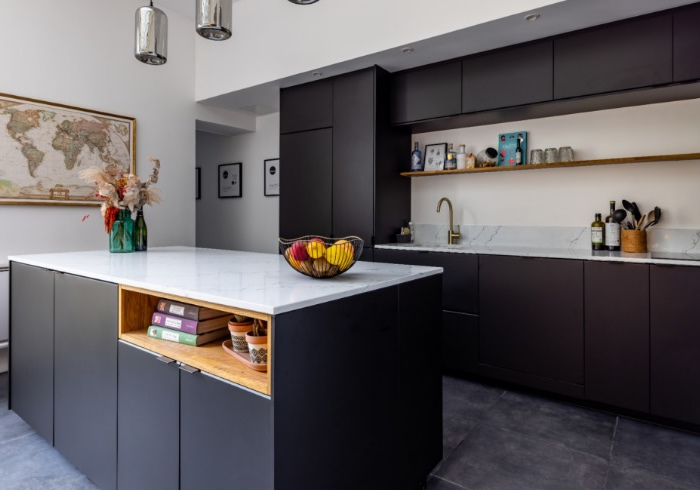 A kitchen with black cabinets and a wooden island.