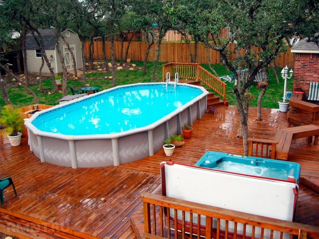 A wooden deck with a pool and hot tub.