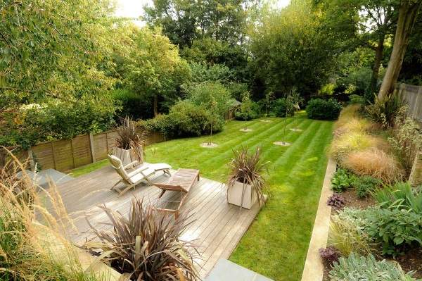 A backyard with a wooden deck and grass.