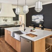 A kitchen with a black island and wood floors.