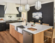 A kitchen with a black island and wood floors.