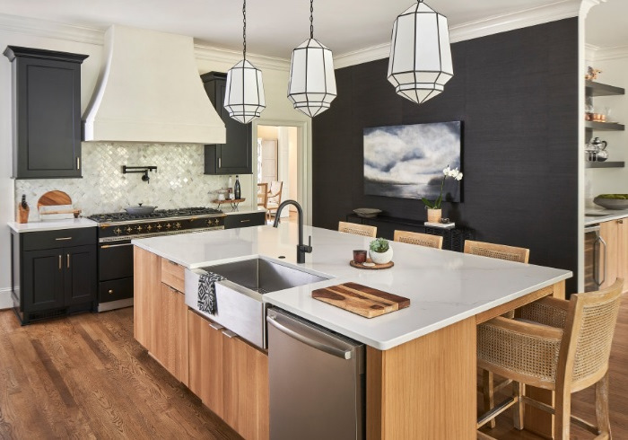 A kitchen with a black island and wood floors.