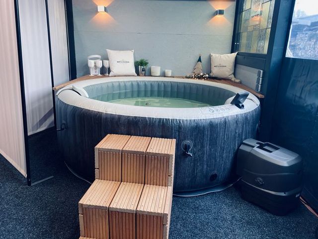 A hot tub in a room with a wooden floor.