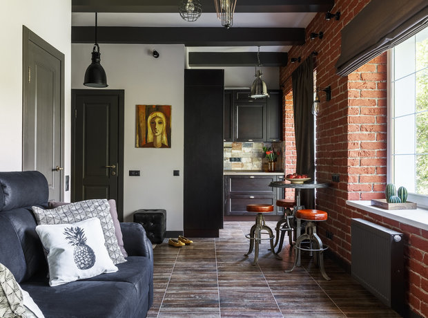 A living room with brick walls and a black couch.