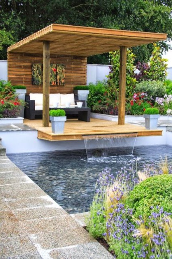 A garden with a wooden deck and a water feature.