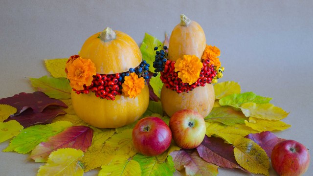 Two pumpkins decorated with flowers and apples.