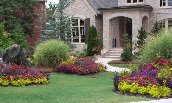 A front yard with flowers and shrubs in front of a house.